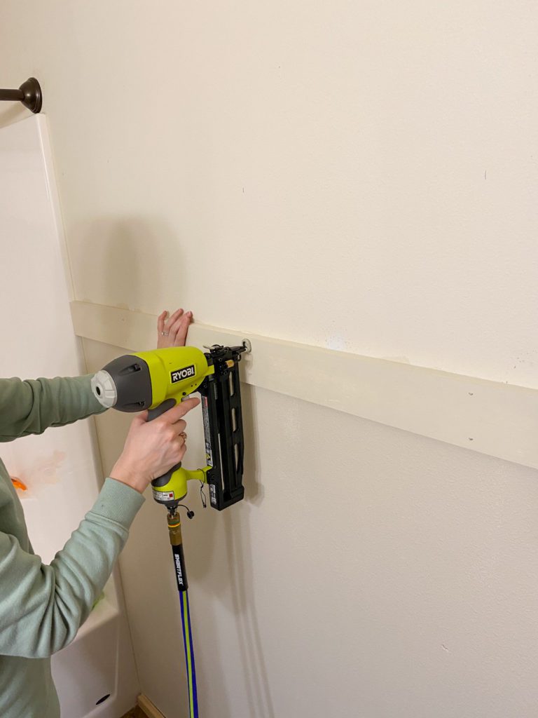 Using a nail gun to secure shiplap to the wall
