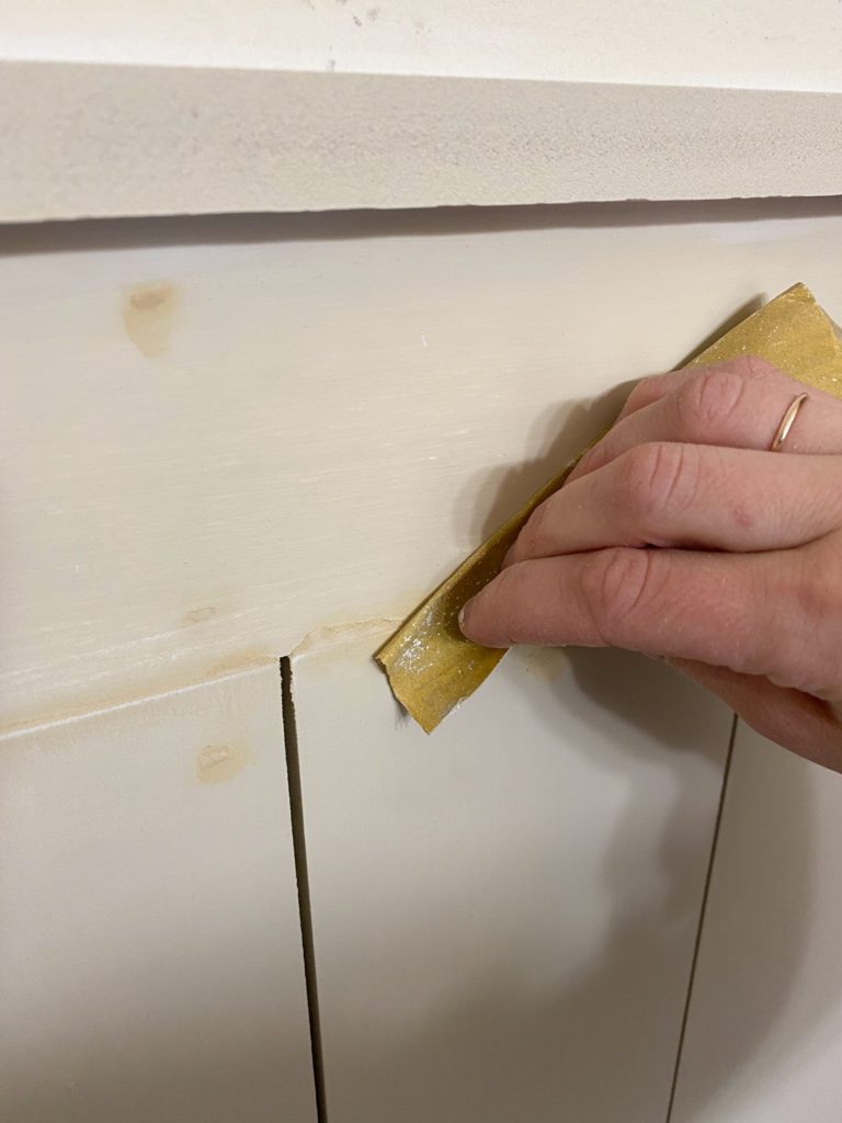 Sanding down wood filler on shiplap wall